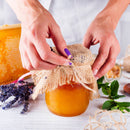 A person doing the finishing touches on a jam jar